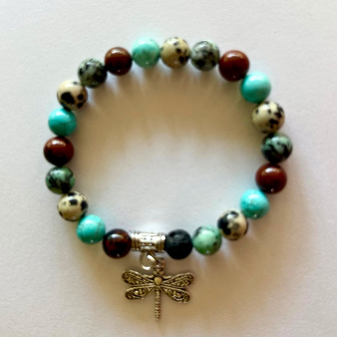 Beaded bracelet with a dragonfly charm on a light background