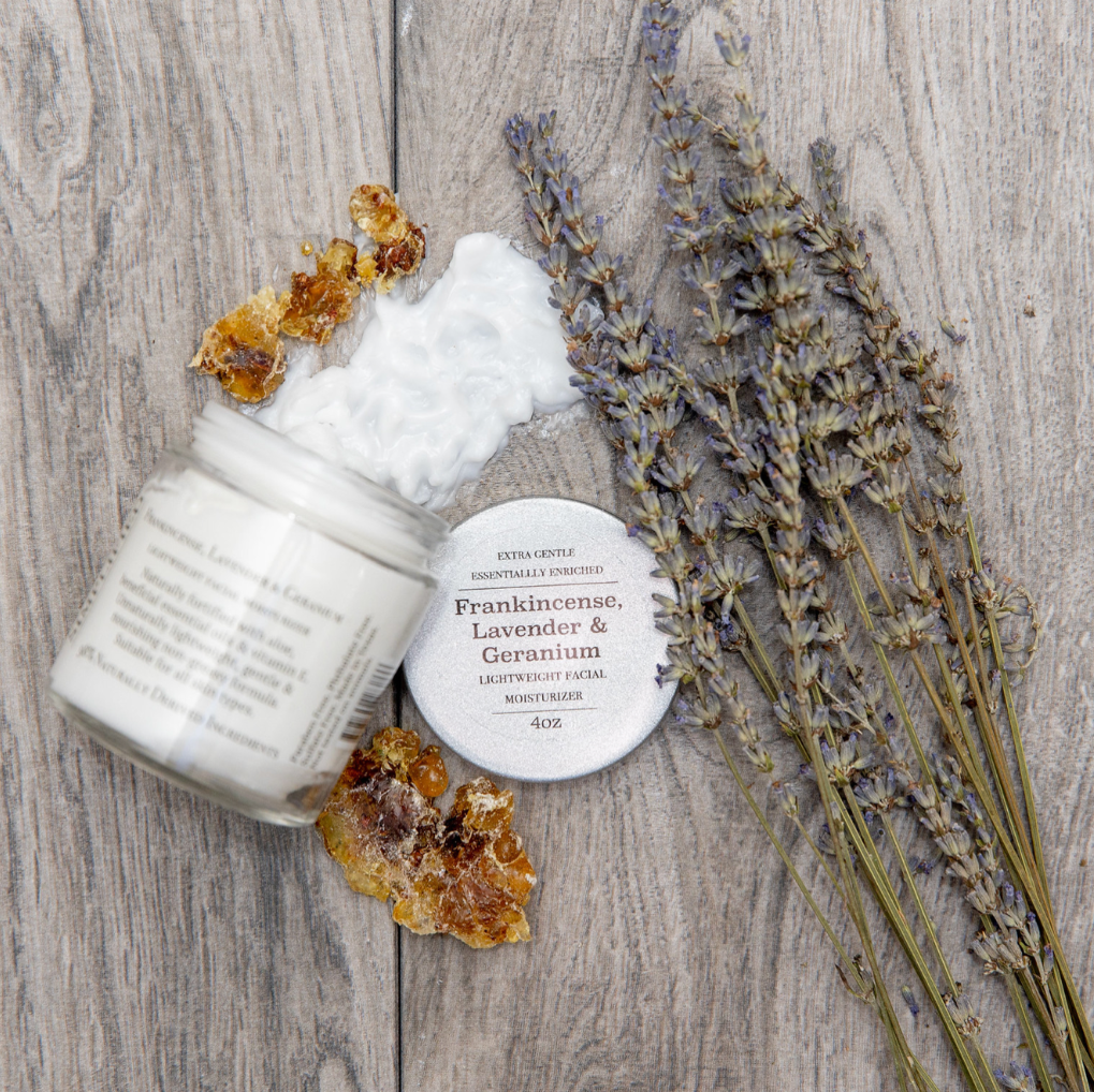 White jar with frankincense, lavender, and geranium essential oils on a wooden surface with dried lavender.