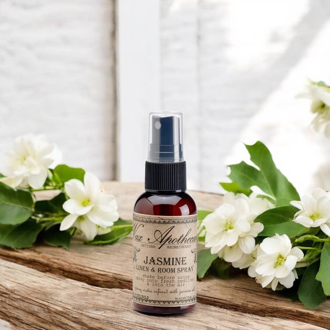 Bottle of Jasmine body spray surrounded by white flowers on a wooden surface